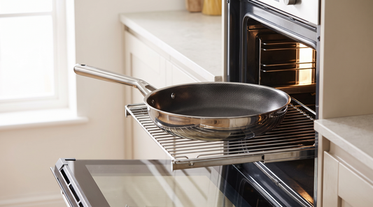 Hive Hybrid stainless steel frying pan resting on an open oven door rack in a bright kitchen